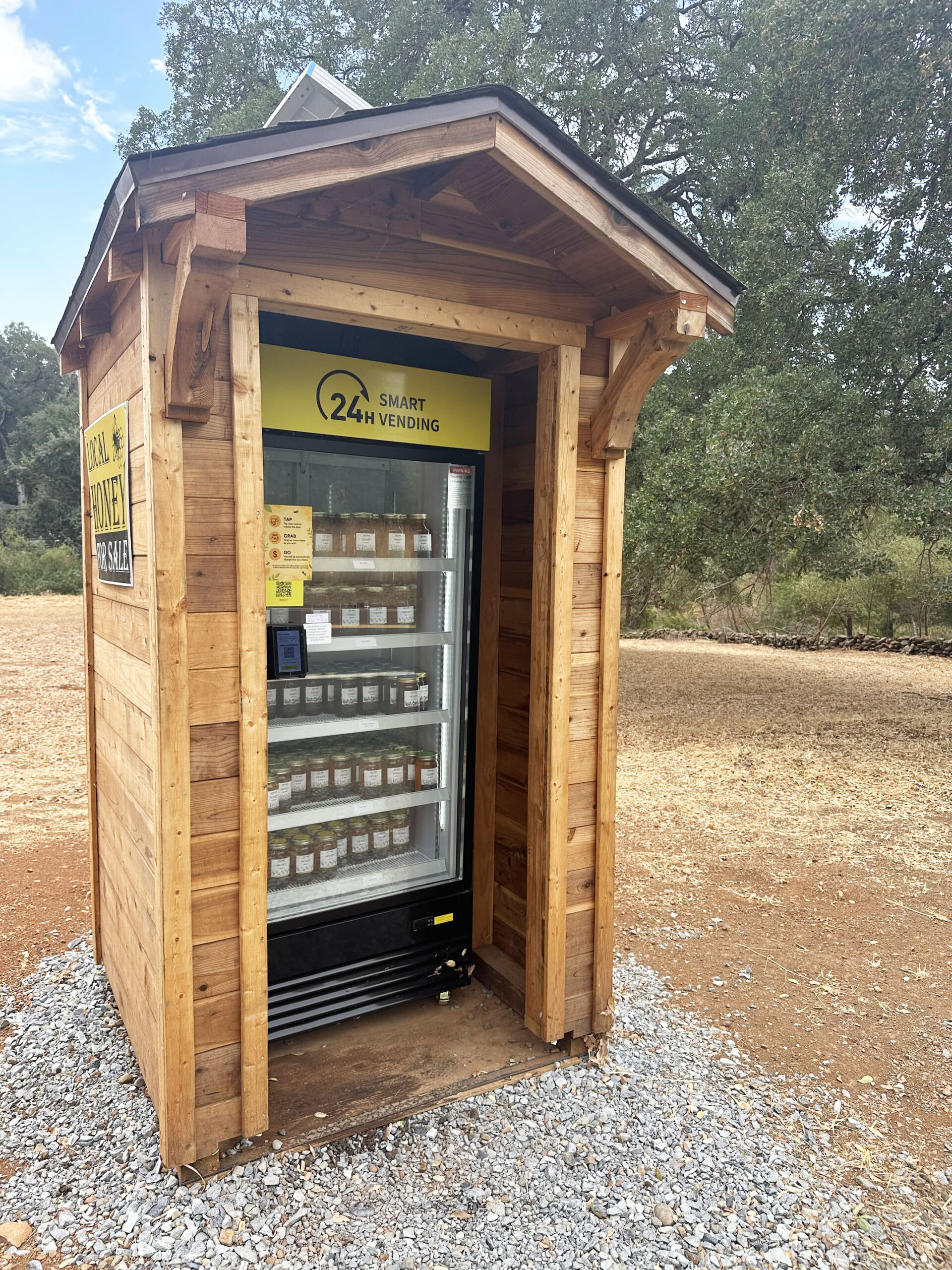 AI smart vending cooler in a custom outdoor wooden kiosk selling local honey